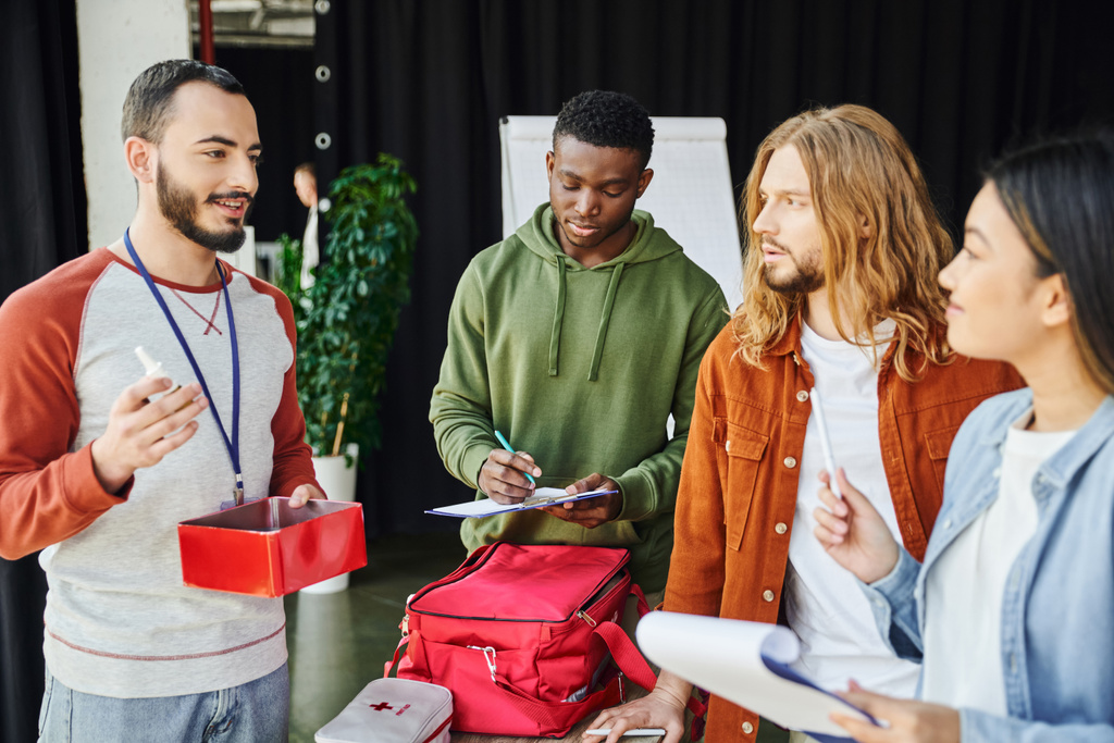 bearded paramedic talking showing first aid kit multicultural
